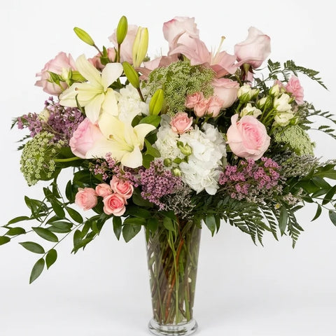 Blush garden-style vase arrangement with roses, lilies, hydrangea and seasonal greenery